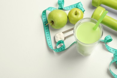 Photo of Tasty shake, apples, measuring tape and powder on white table, above view with space for text. Weight loss
