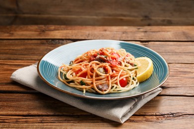 Delicious pasta with anchovies, tomatoes and parmesan cheese on wooden table