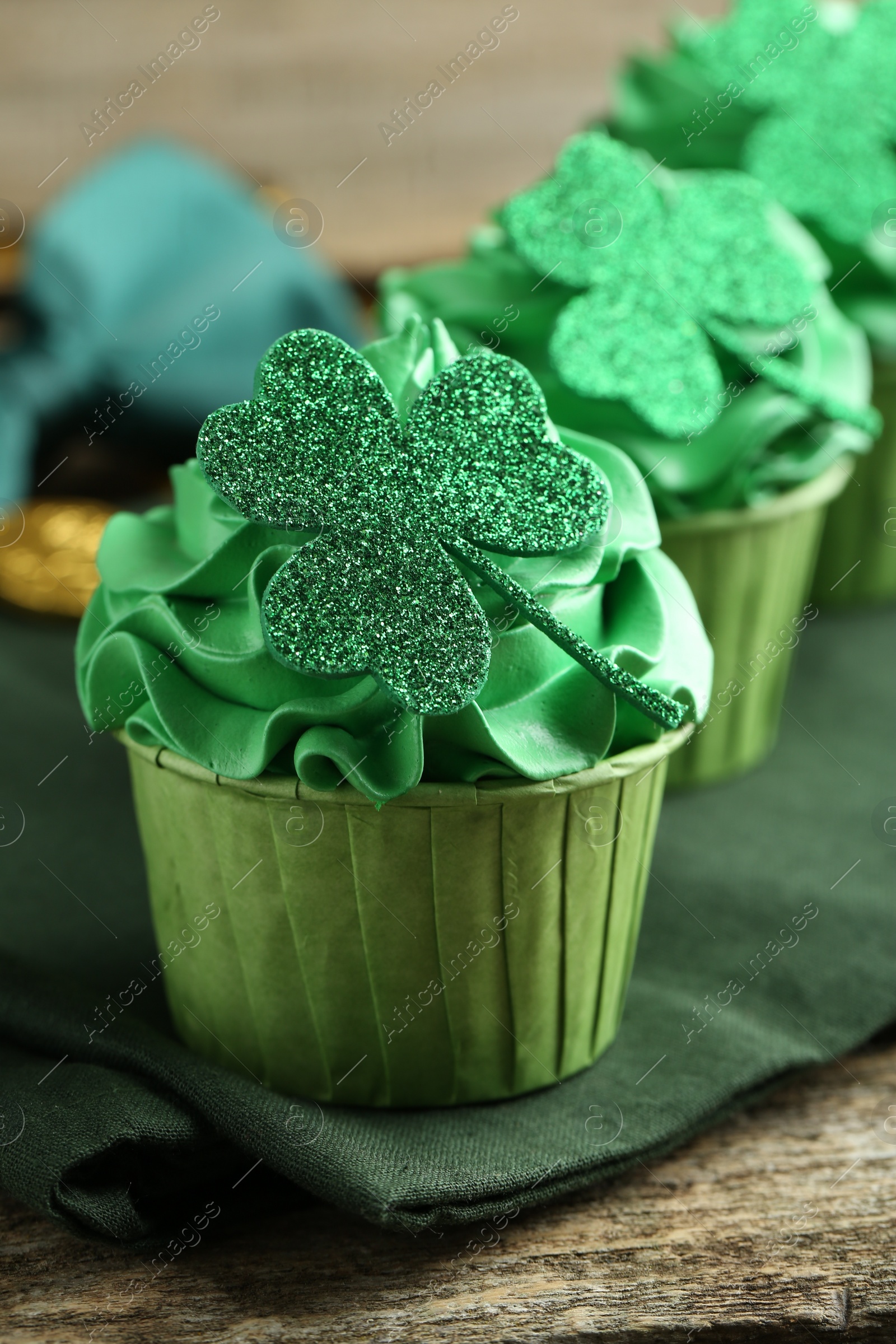 Photo of St. Patrick's day party. Tasty cupcakes with clover leaf toppers and green cream on wooden table, closeup