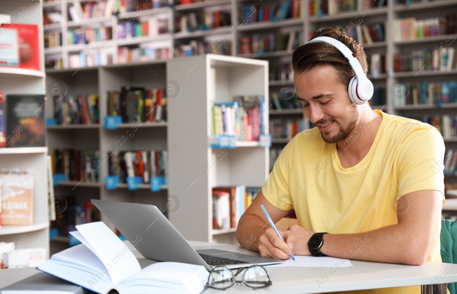 Photo of Young man studying at table in modern library