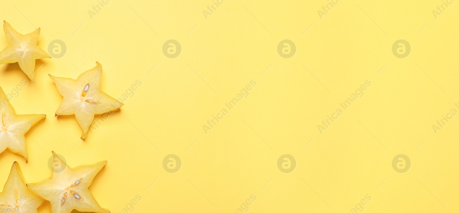 Photo of Delicious carambola slices on yellow background, flat lay. Space for text