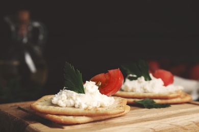 Photo of Delicious crackers with cream cheese, tomato and parsley on wooden board, closeup