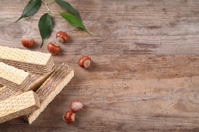 Photo of Delicious wafers with hazelnuts on brown wooden background. Space for text