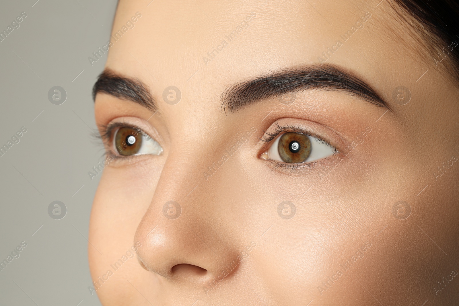 Photo of Young woman with beautiful eyebrows on grey background, closeup