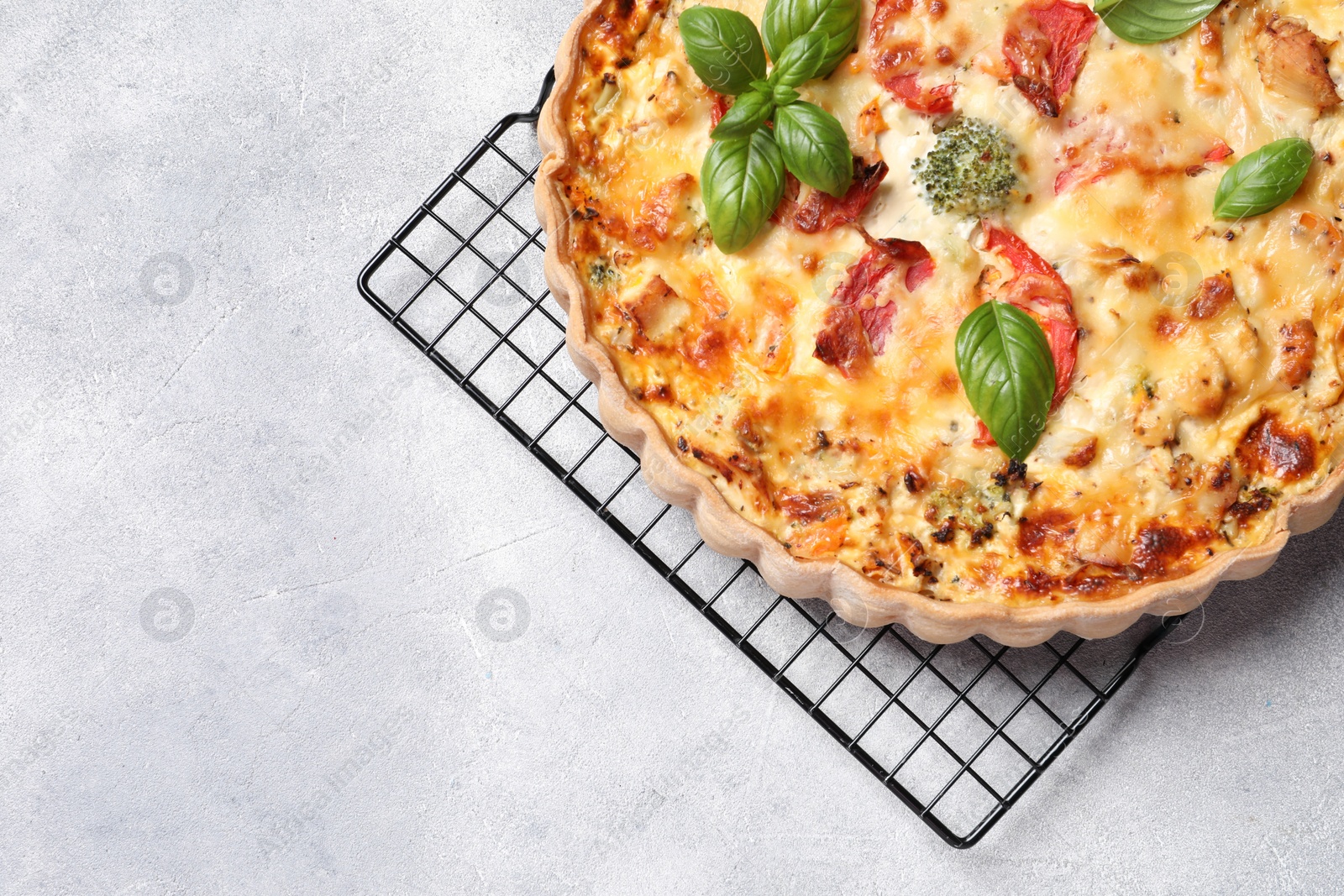 Photo of Tasty quiche with tomatoes, basil and cheese on light textured table, top view. Space for text