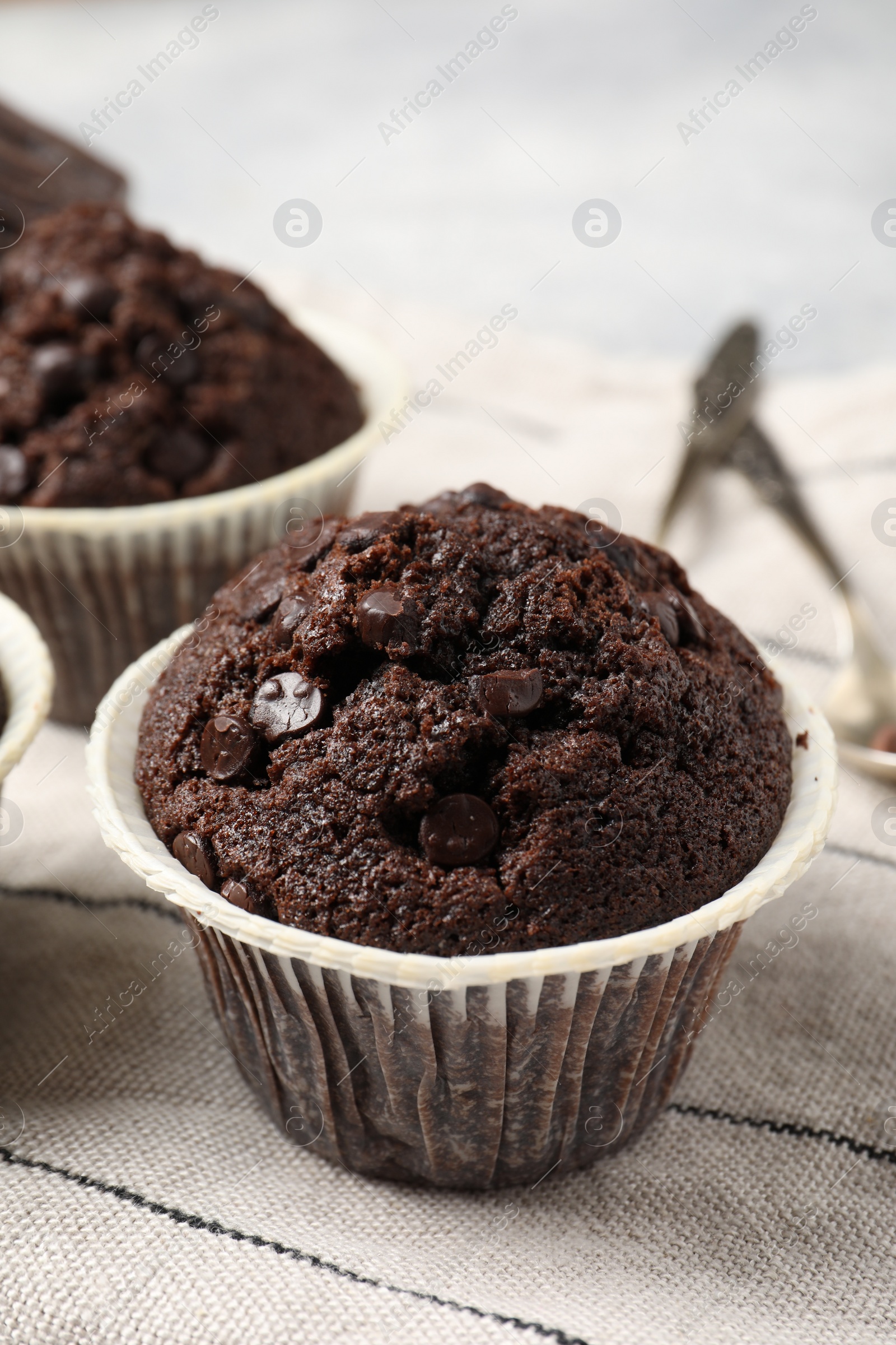 Photo of Tasty chocolate muffins and cloth on table, closeup