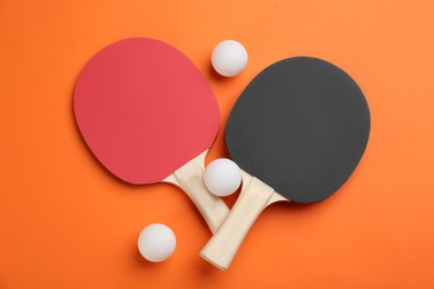 Photo of Ping pong rackets and balls on orange background, flat lay