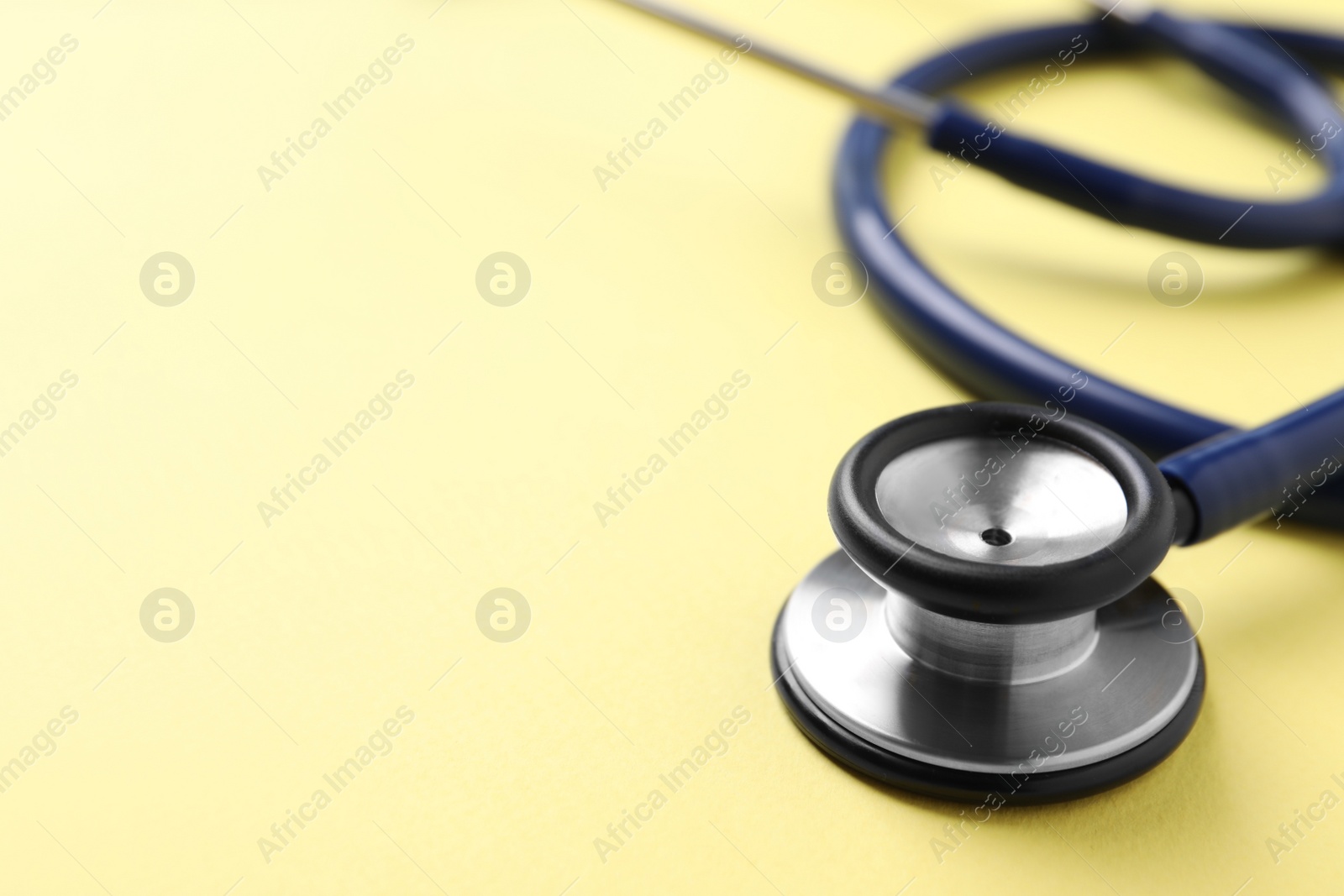 Photo of Stethoscope on yellow background, closeup. Space for text