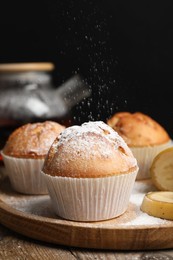 Photo of Tasty muffins served with banana slices on wooden table against dark background