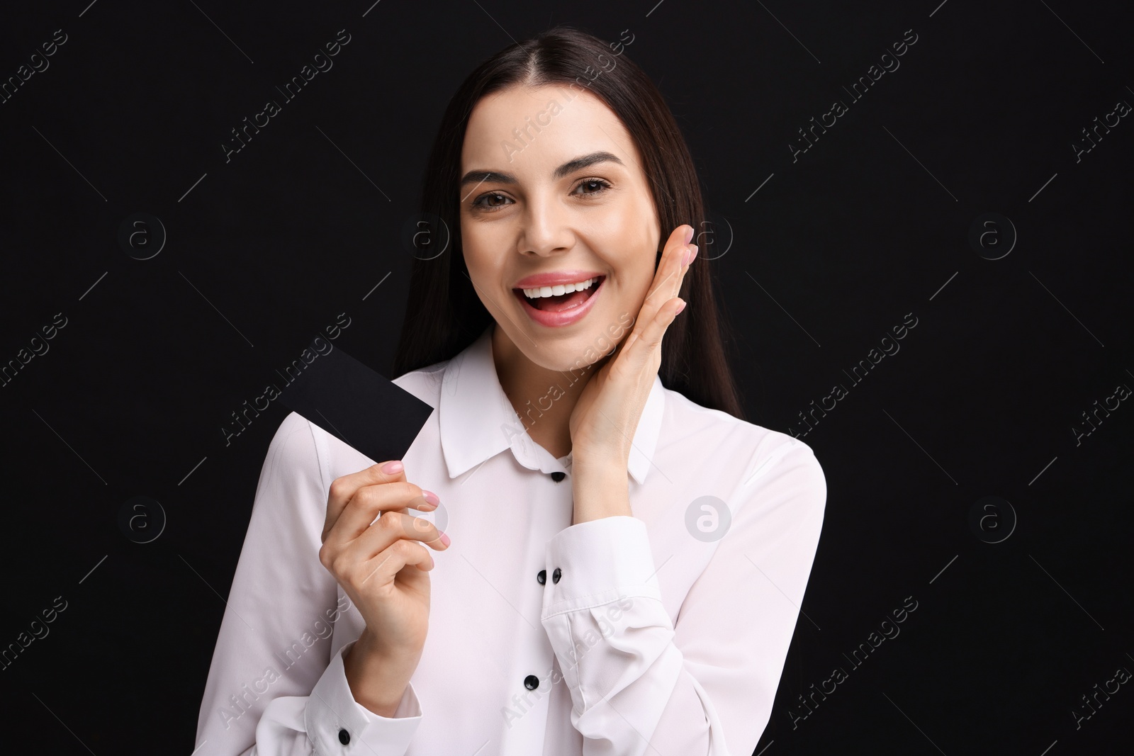 Photo of Happy woman holding blank business card on black background