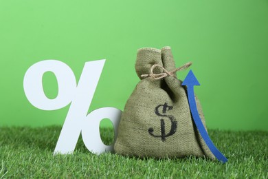 Photo of Bag with money, up arrow and percent symbol against green background. Profit concept