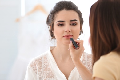 Photo of Professional makeup artist working with young woman in salon