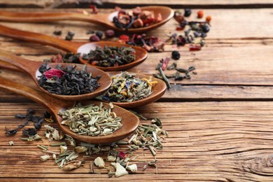 Composition with different teas and spoons on wooden table. Space for text