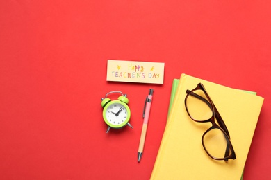 Photo of Flat lay composition of card with inscription HAPPY TEACHER'S DAY and stationery on red background, space for text