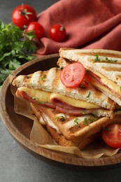 Photo of Tasty sandwiches with ham, tomato and melted cheese in bowl on grey table, closeup