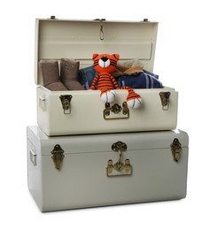 Stylish storage trunks with warm clothes, shoes and tiger toy on white background. Interior elements