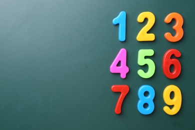 Photo of Colorful numbers on green background, flat lay. Space for text