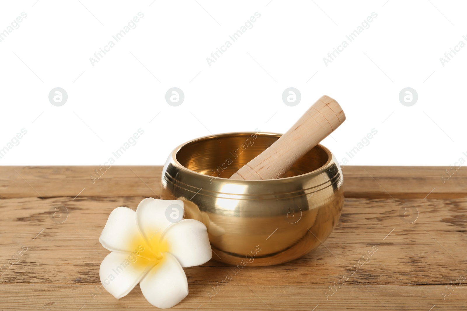 Photo of Golden singing bowl, mallet and flower on wooden table against white background