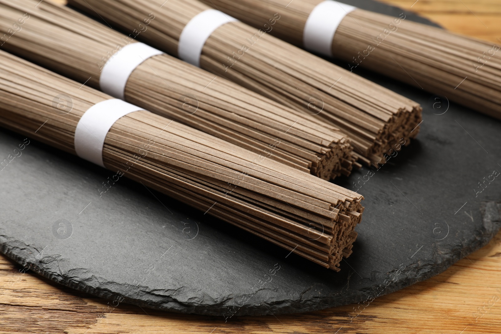 Photo of Uncooked buckwheat noodles (soba) on wooden table, closeup