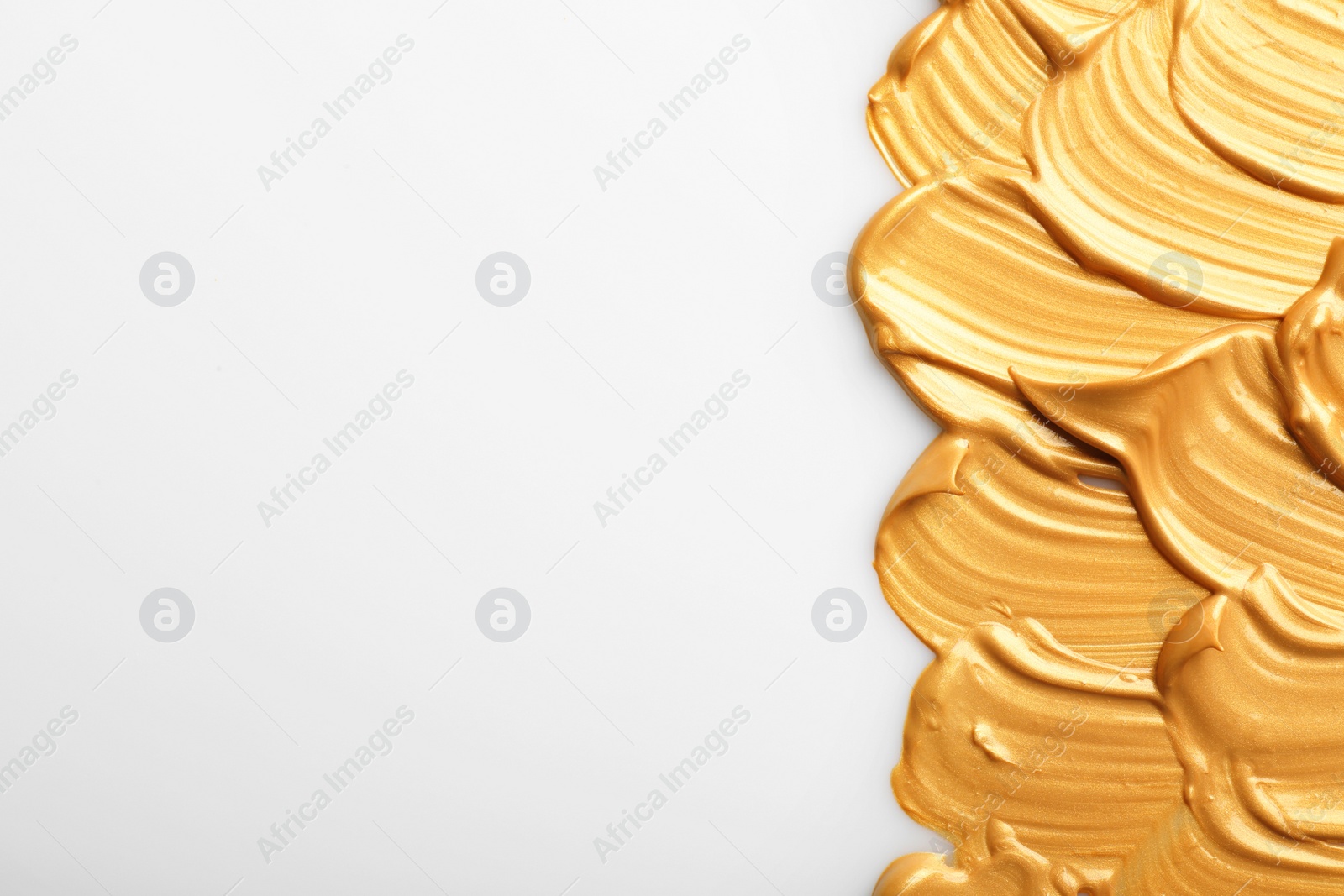 Photo of Strokes of gold paint isolated on white, top view