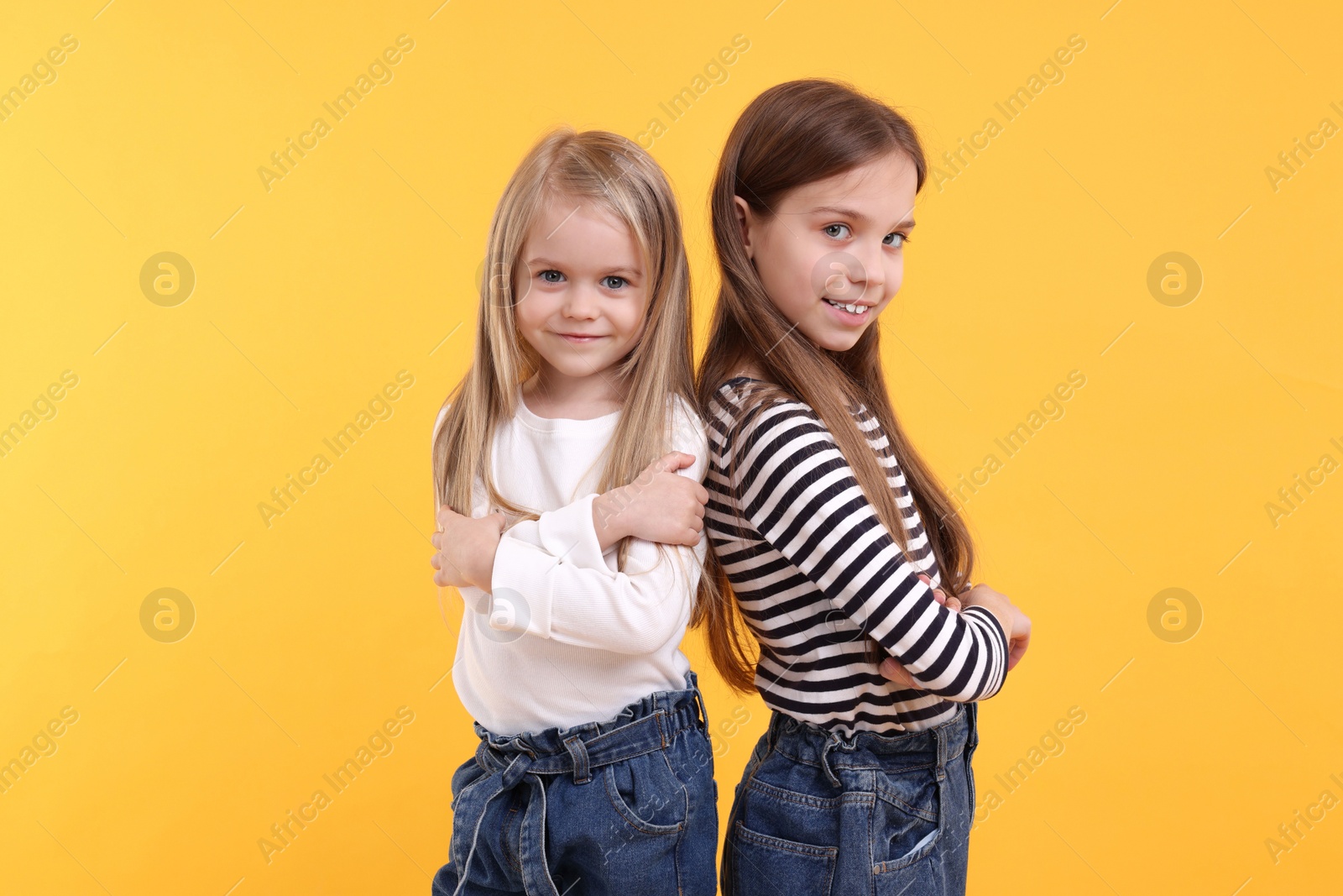 Photo of Portrait of cute little sisters on orange background