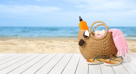 Image of Summer vacation. Bag with sunscreen and accessories on sunny ocean beach, space for text. Banner design