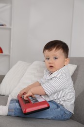 Photo of Cute little boy with toy piano at home