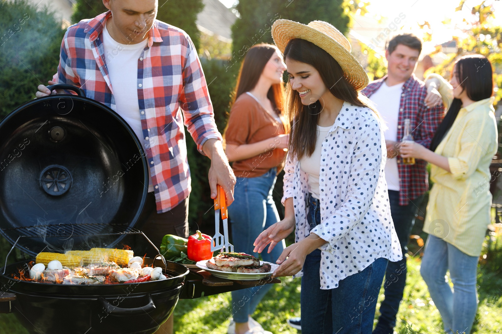 Photo of People with drinks having barbecue party outdoors