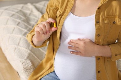 Photo of Pregnant woman taking pill on bed, closeup