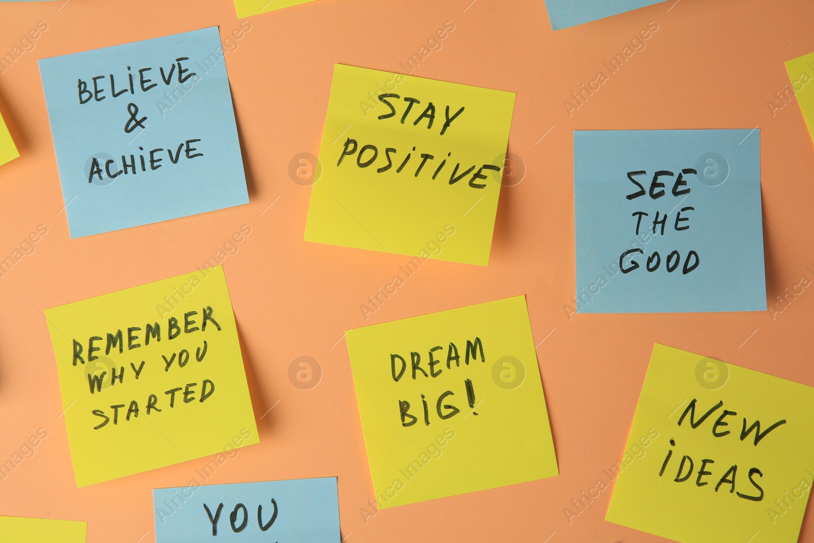 Photo of Paper notes with life-affirming phrases on pale orange background