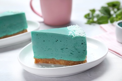 Photo of Piece of tasty spirulina cheesecake on grey table