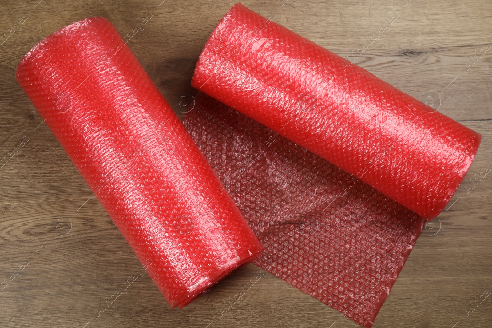 Photo of Bubble wrap rolls on wooden background, flat lay