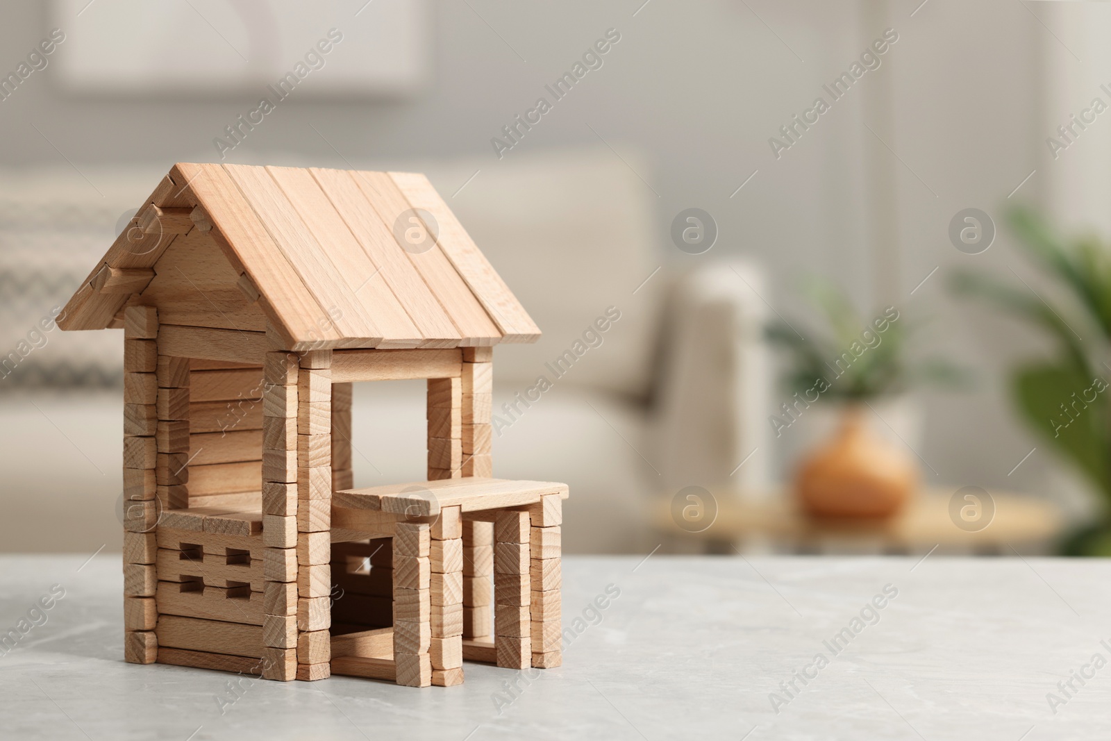 Photo of Wooden house on light grey table indoors, closeup. Space for text. Children's toy