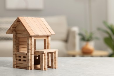 Photo of Wooden house on light grey table indoors, closeup. Space for text. Children's toy