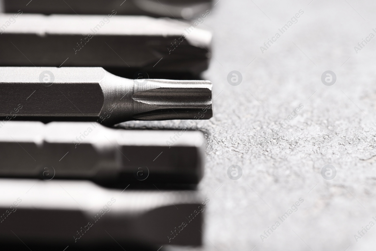 Photo of Different screwdriver bits on grey table, closeup