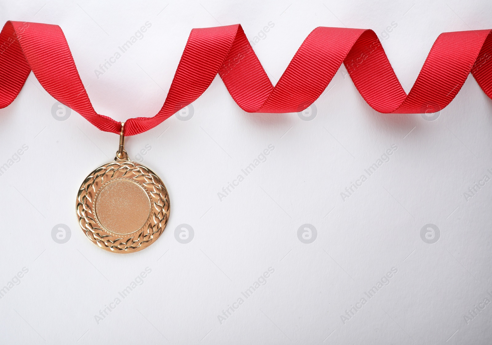 Photo of Gold medal on white background, top view with space for text. Symbol of victory