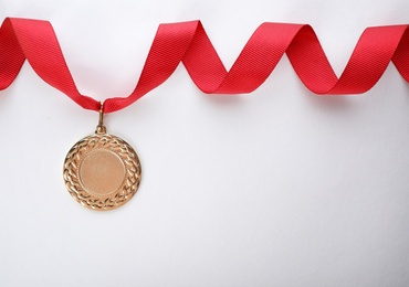 Gold medal on white background, top view with space for text. Symbol of victory