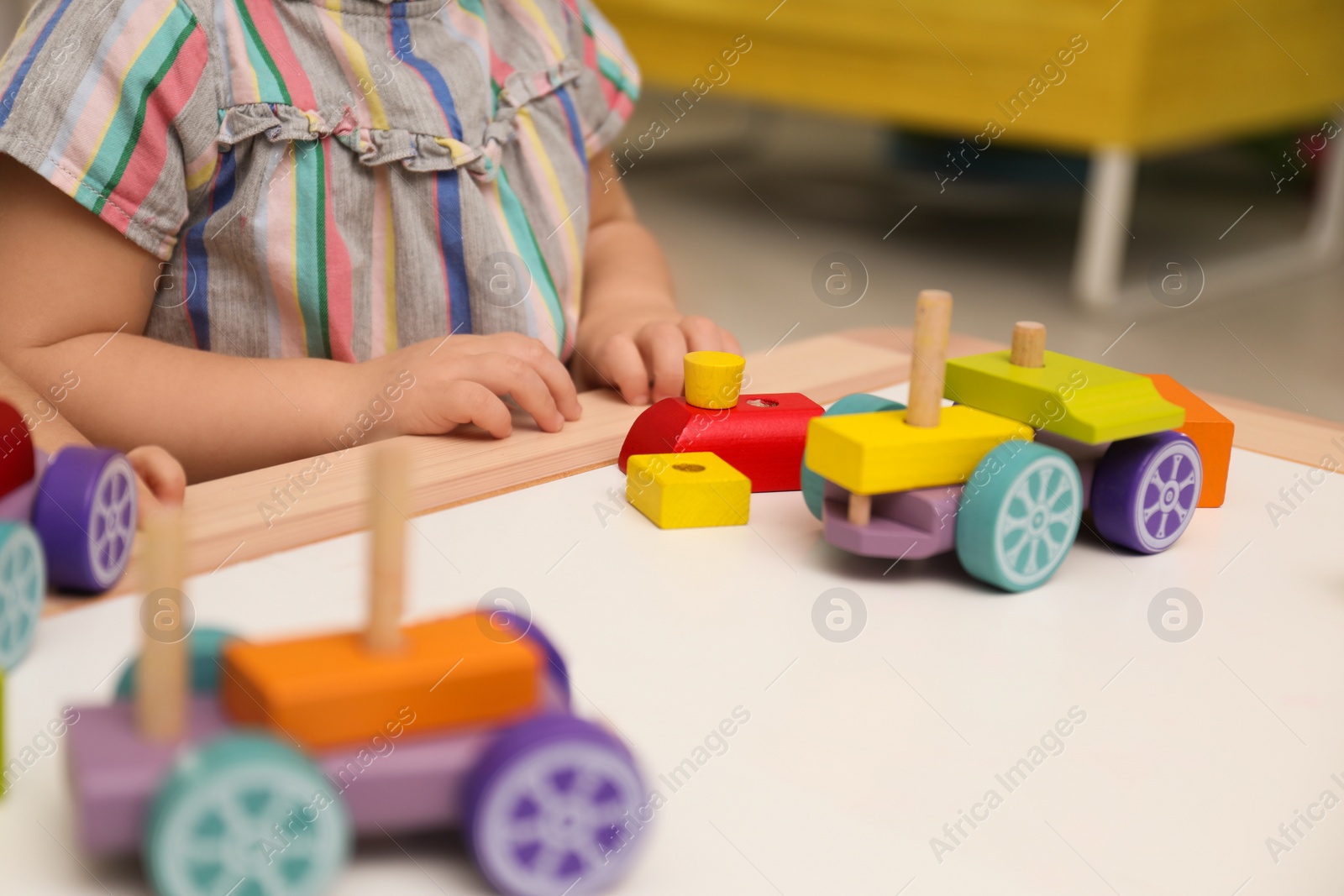 Photo of Little child playing with construction set at table, closeup
