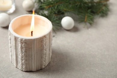 Candle and Christmas decor on grey table, space for text