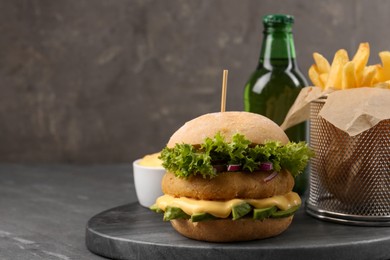 Tasty vegetarian burger served with french fries and beer on black table, space for text