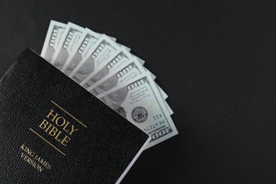 Holy Bible with money on black background, top view. Space for text