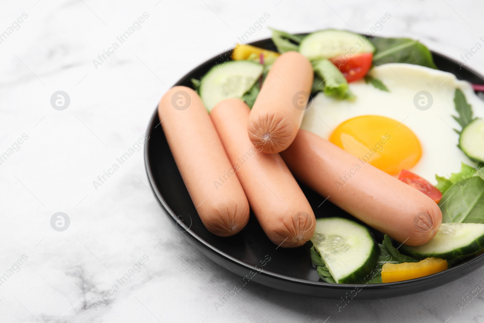 Photo of Delicious breakfast with boiled sausages and fried egg on white marble table, closeup