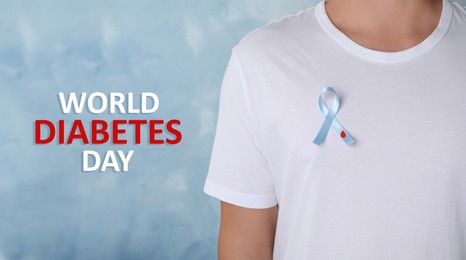 Image of Man with light blue ribbon and paper blood drop on color background, closeup. World Diabetes Day