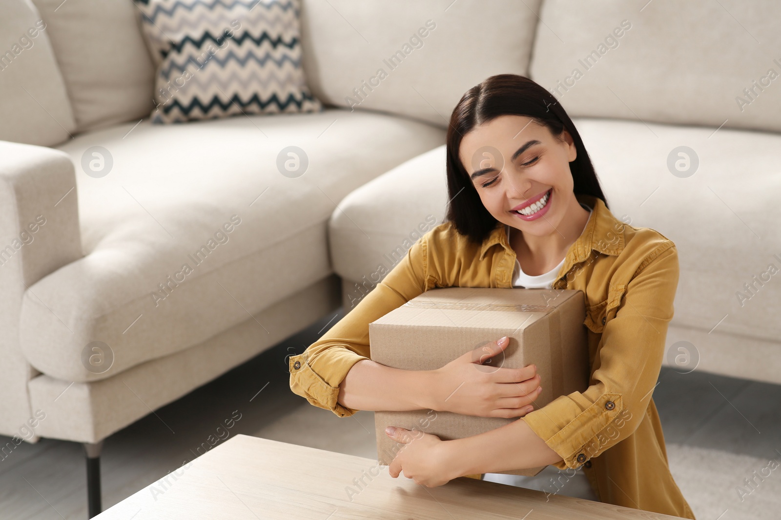 Photo of Happy young woman with parcel at home. Internet shopping