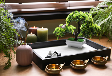 Photo of Beautiful miniature zen garden, candles and oil lamps near window indoors