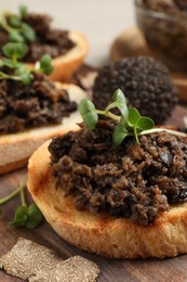 Photo of Delicious bruschettas with truffle sauce and microgreens on wooden table, closeup