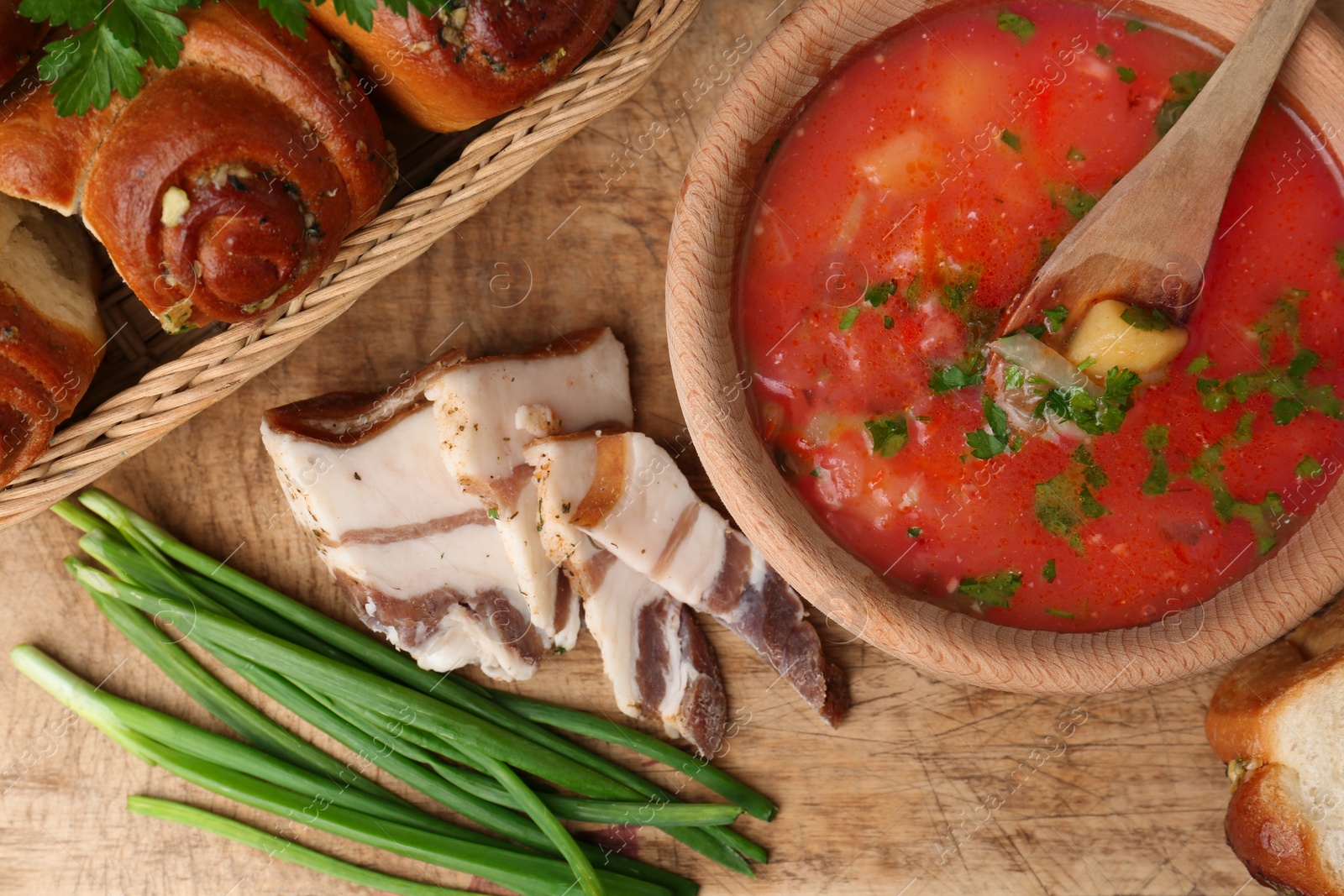 Photo of Delicious borsch served with pampushky and salo on wooden table, flat lay. Traditional Ukrainian cuisine