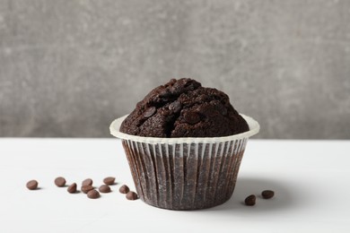 Photo of Tasty chocolate muffin on white table against grey background