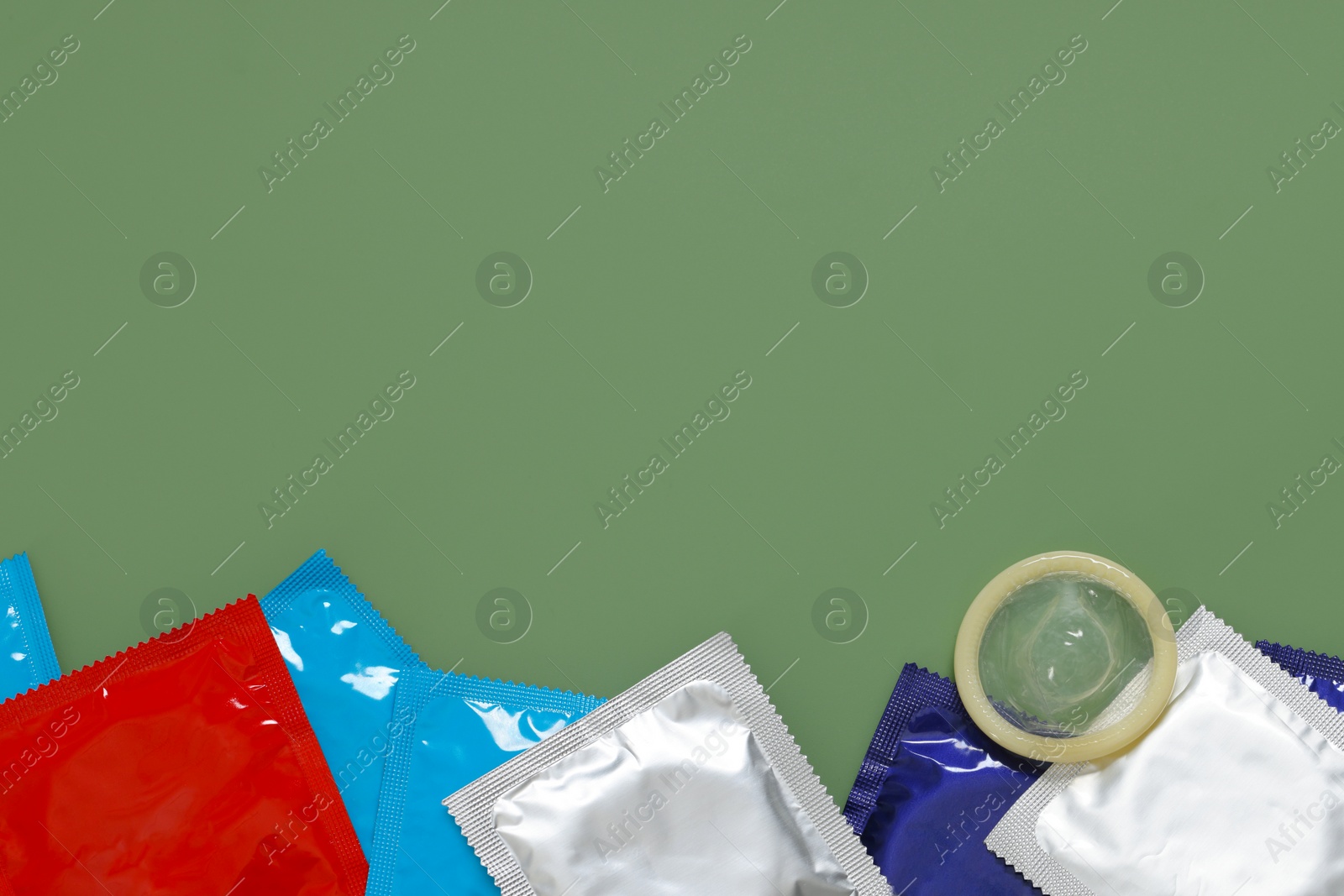 Photo of Packaged condoms on light green background, top view with space for text. Safe sex