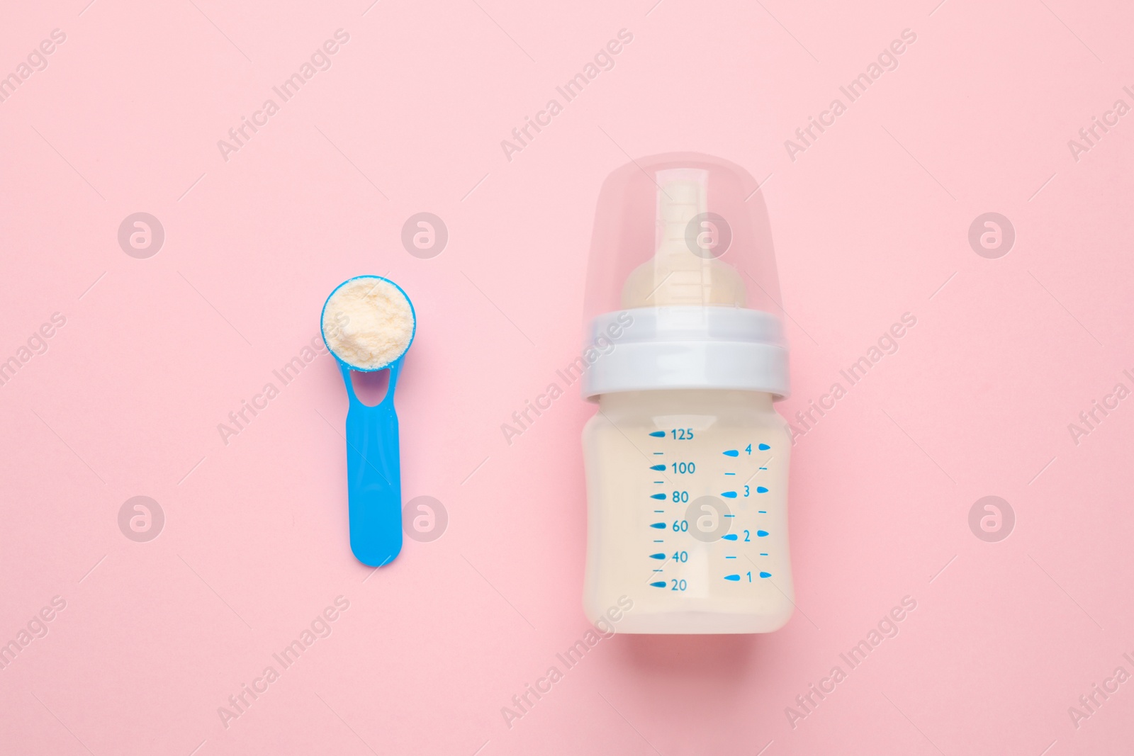 Photo of Feeding bottle with infant formula and powder on pink background, flat lay